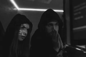 A man and a woman in black hoods looking off into the distance